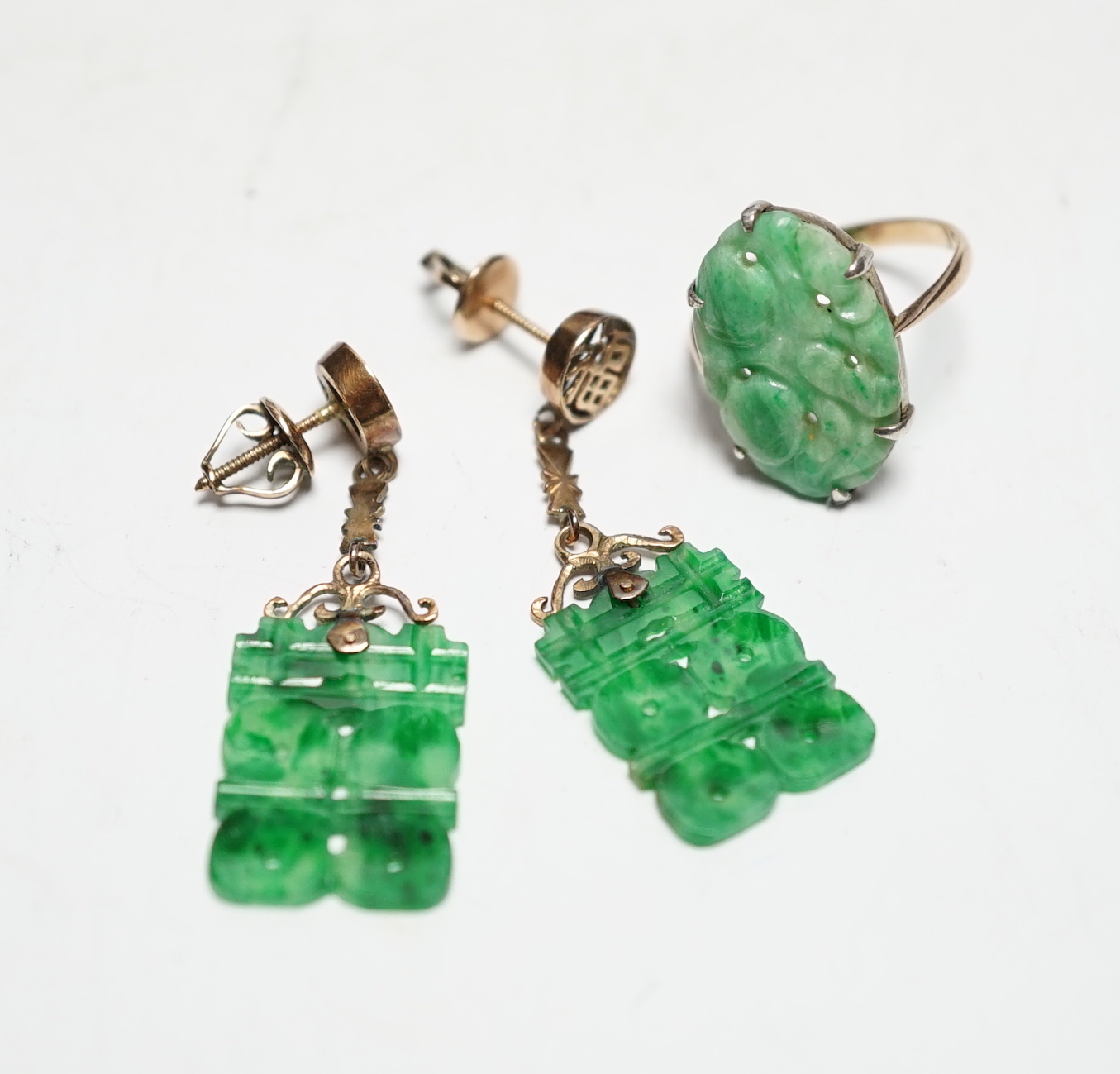 A pair of Chinese 14k yellow metal and jade set drop earrings, 37mm and a yellow metal and carved oval jade set ring, gross weight 6.1 grams.